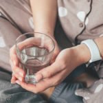 Young woman holding glass with water in hands. Self care concept. Formation of healthy useful habit. Authentic lifestyle moment